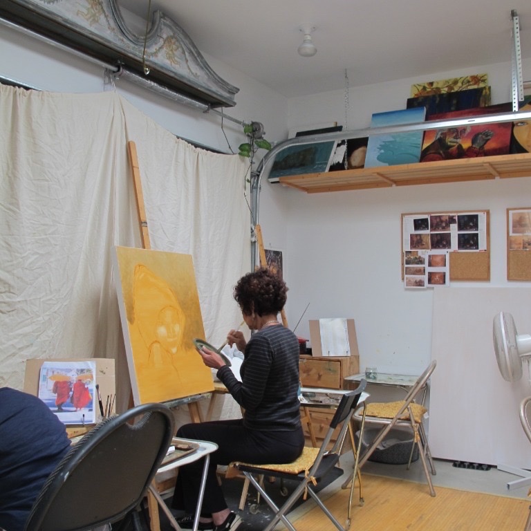 Natty Saidi painting at her easel in the studio